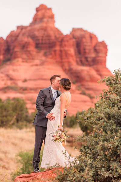 bride and groom kissing in front of Sedona red rock wedding