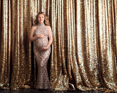 Sophisticated maternity portrait with a mother-to-be in a shimmering gold gown against a sparkling backdrop, captured in Overland Park, Kansas. Perfect for families seeking glamorous and high-end maternity photography in the Kansas City area.