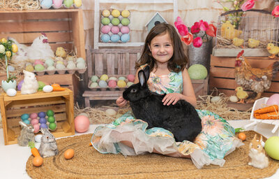 Frozen Moments by Kathy Photography | Easter photo session with little girl holding a large black rabbit on a background of easter eggs.