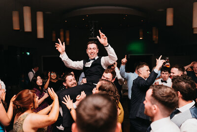 Groom being lifted in the air by wedding guests on the dance floor at Castle Dargan in Sligo Ireland