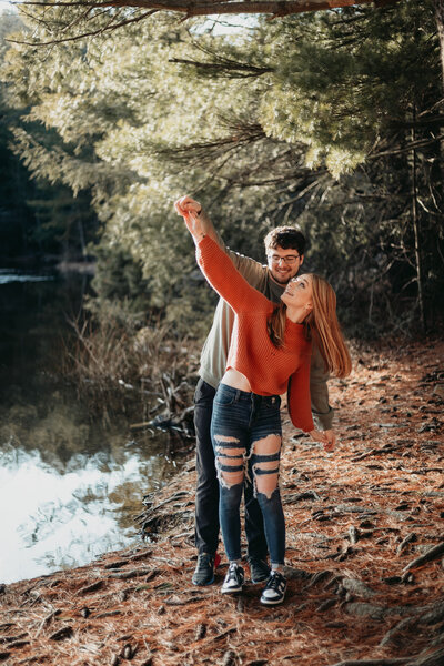 Playful couple dancing in a wooded area during their engagement session in Central Pennsylvania. 