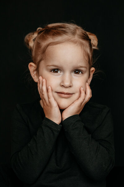 portret van een meisje met haar handjes bij haar wangen