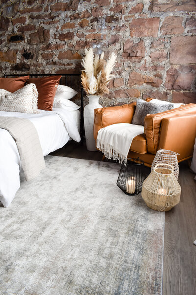 Boho lanterns sit on the floor in front of a large brown leather armchair