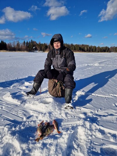 Asiakas on osallistunut pilkkimiretkelle ja kuvassa hän pilkkii kauniissa talvimaisemassa.