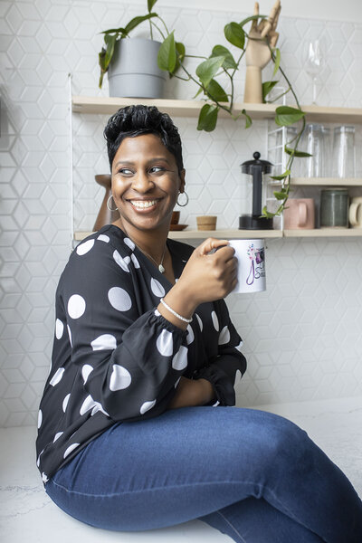 Metro Detroit Senior Photographer with short pixie haircut in black polka dot blouse and blue jean jeggings posing casually