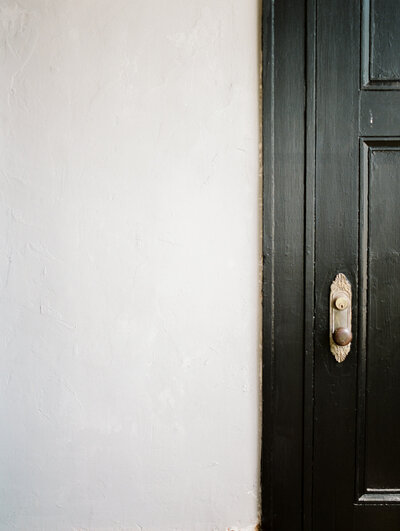 black door with ornate brass antique vintage knob detail, textured light color wall, film brand photography in Michigan