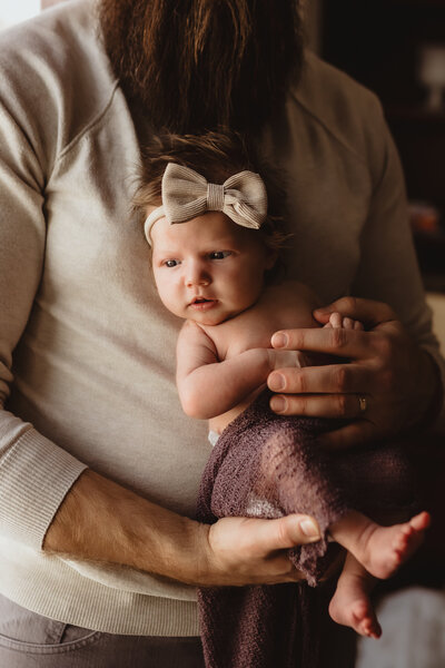 FATHER HOLDING NEWBORN DAUGHTER IN NURSERY