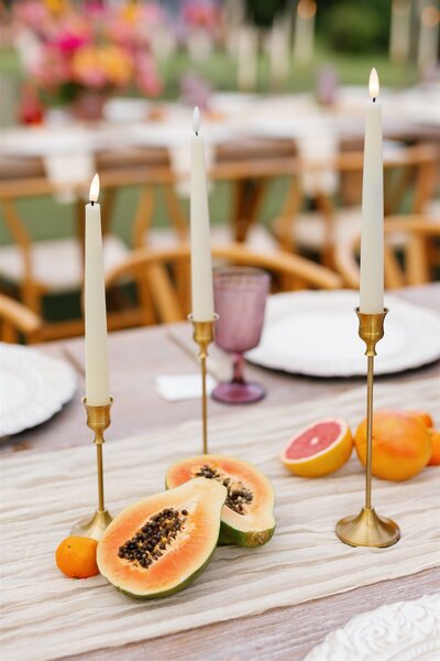 Tall candles and cut fruit on a wedding reception table 