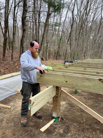 A Shrewsbury MA Deck Builder Hard At Work Measuring Supports