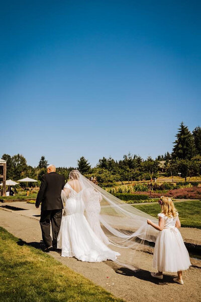 bride walking down the aisle in her custom pearl veil with the father of the bride
