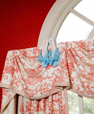 Photo of blue wedding shoes sitting on red pattered curtains taken by Portland Maine wedding photographer