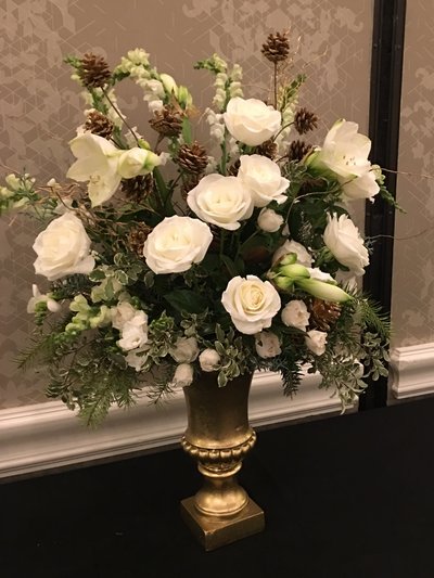 Large white floral arrangement in a gold urn