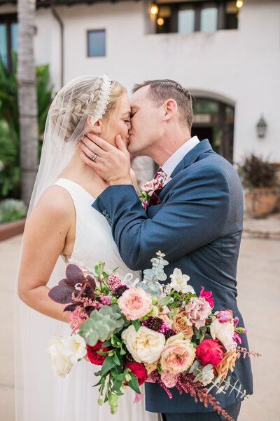 Wedding couple kissing while bride holds her flowers