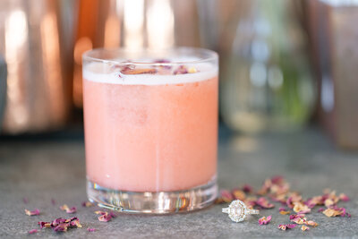 signature cocktail and engagement ring on the bar at Mela Kitchen