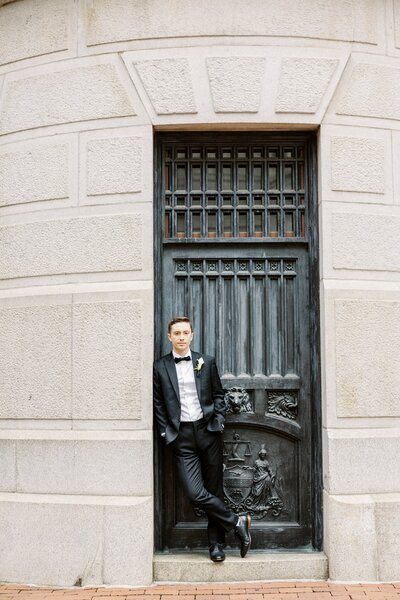 Groom posing in front of large iron door