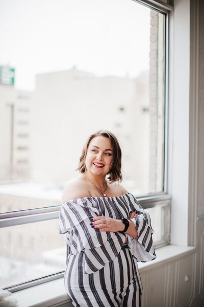 Picture of Bree smiling while leaning against a window sill