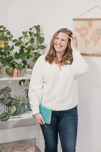 SEO strategist Julia Bocchese standing by plants holding a notebook