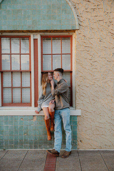 arkansas photo of couple in a window going in for a kiss during their engagement photos