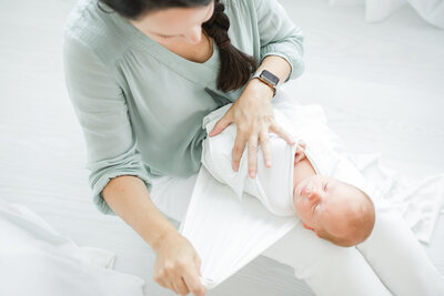 Newborn photographer, Kristin Wood, swaddles sleeping newborn baby during newborn photography session