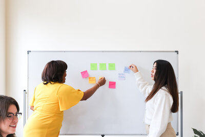 2 Firefly team members collaborate with sticky notes on a white board