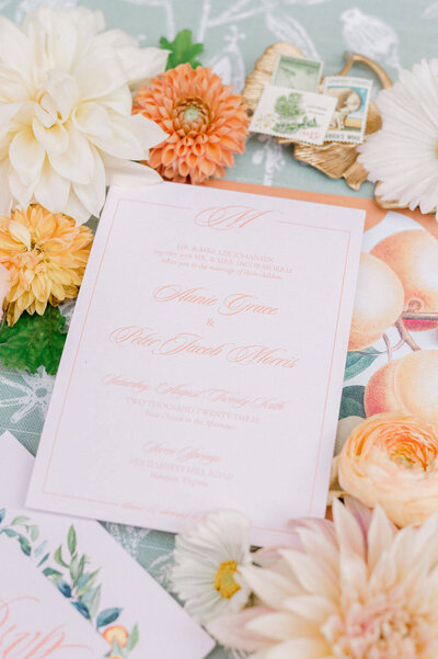 Luxury wedding invitation suite with peach lettering, styled with florals and vintage details.