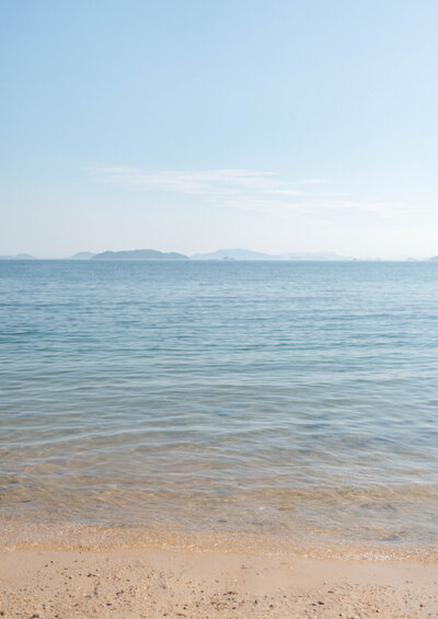 Peaceful view of the calm Setonaikai Sea in Hiroshima, with soft waves and a serene coastal horizon.