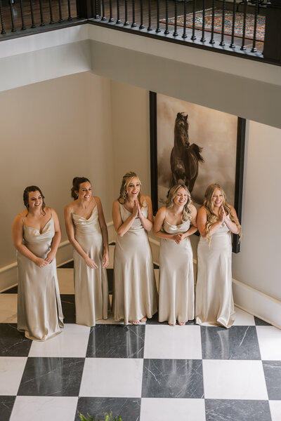 Bridesmaids standing in the entry way of hazelnut farms watching the bride walk down for a first look. The bridesmaids are crying and emotional in the shot. 