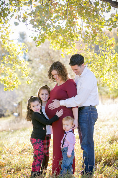 Family group hug with pregnant mom in the middle at Cheeseman Park