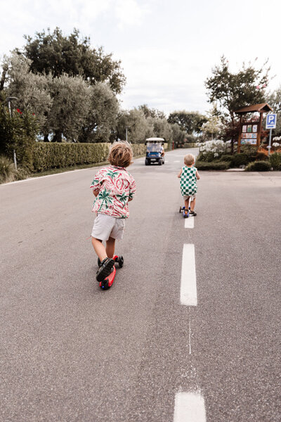 twee jongetjes steppen op brede weg op camping