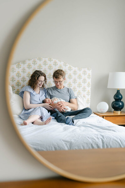 Philadelphia couple holds newborn baby on their bed in this reflection in the mirror photo