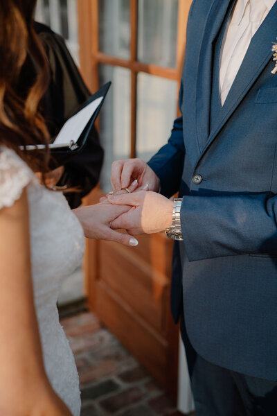 photo of groom putting ring on brides hand