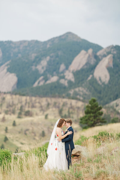 Two brides pose in front of mountains at this LGBTQIA+ destination wedding near the Chautauqua trail. Photo by Claire Katan.
