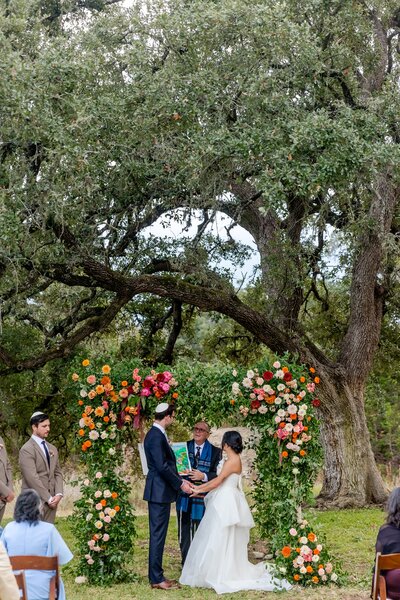 Hill country wedding ceremony with floral arch