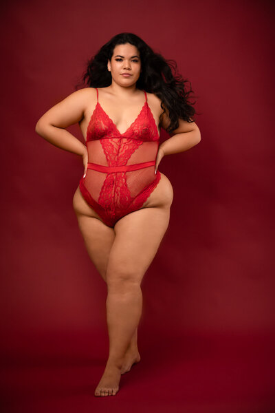 woman with long dark hair wearing a red on piece lingerie