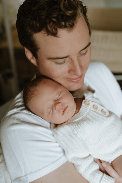 A Brisbane father holds his sleeping baby daughter against his chest