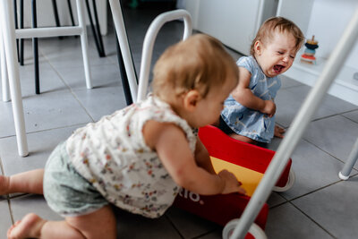 A little girl crying as her twin sister took her toy