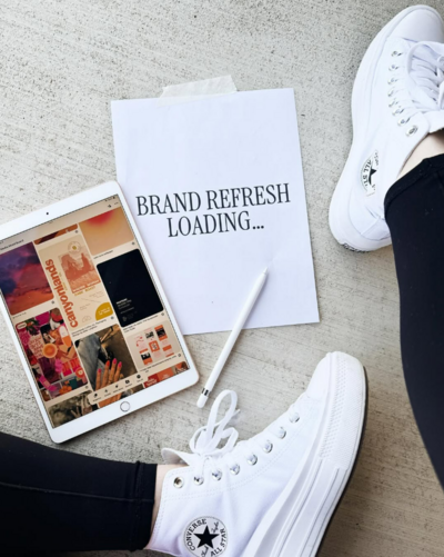image showing a piece of paper with the text "brand refresh loading" next to an ipand and white sneakers