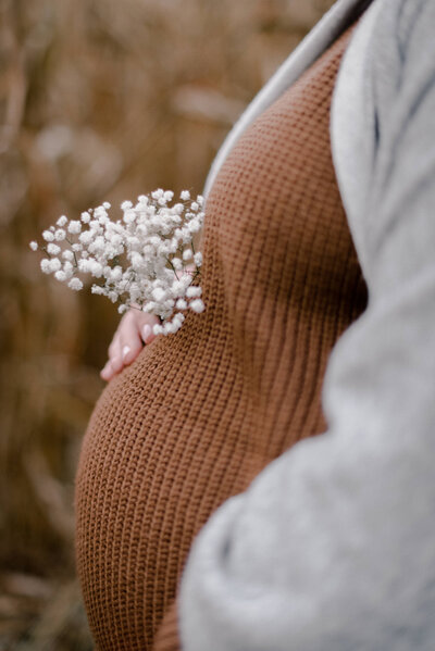 Nahaufnahme eines süßen Babybauchs mit weißem Schleierkraut dekoriert.