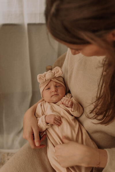 Mama kijkt pasgeboren dochter liefdevol aan tijdens newbornshoot
