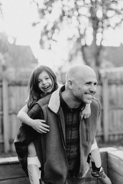 black and white image of daughter on her fathers back