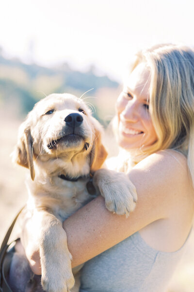 pale young puppy with too-big paws looks smug as her person smiles at her