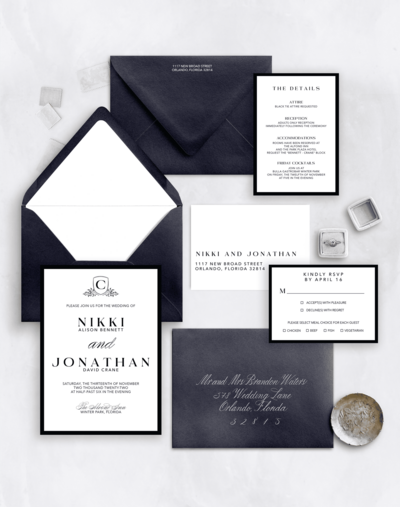 Flat lay of a black and white wedding invitation suite with bold typography and dark envelopes.