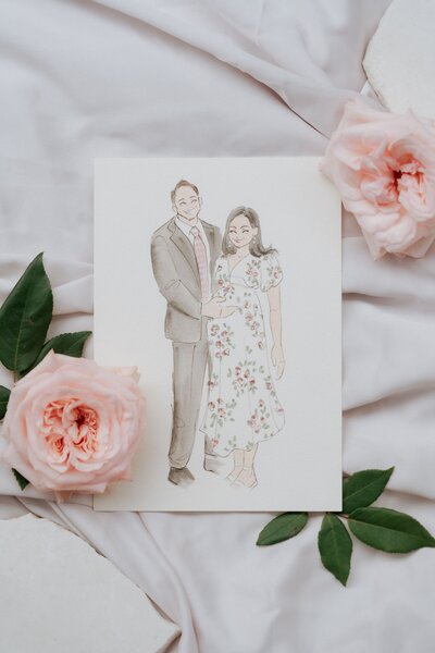 Watercolor illustration of a smiling couple, with blush pink roses and greenery around the artwork.