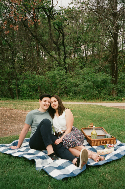 A couple sitting on a blanket during a picnic.