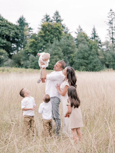 Man and woman standing in field with four young children