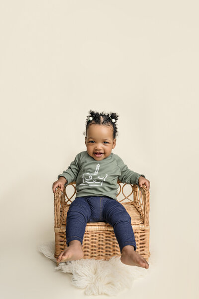 one year old little girl smiles wearing green shirt and pants during her one  year old milestone session