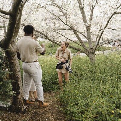 A couple laughing with their photographer in a grassy field 