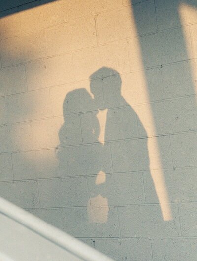 shadows of a couple kissing on a wall illuminated by warm sunset photographed in minnesota by tom thornton