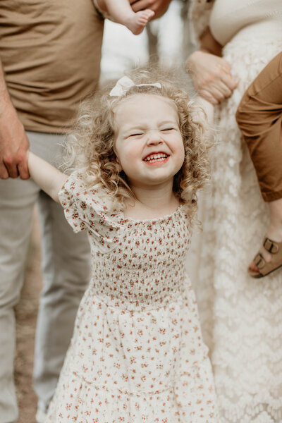 Candid shot of a child grinning ear to ear during a family photoshoot.
