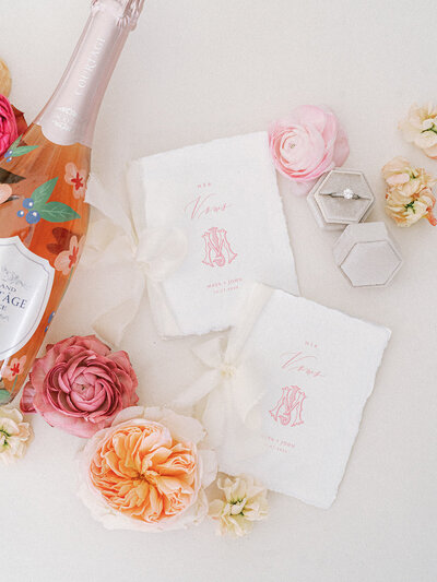 Flat lay of wedding invitation suite with the wedding rings and pink and orange flowers